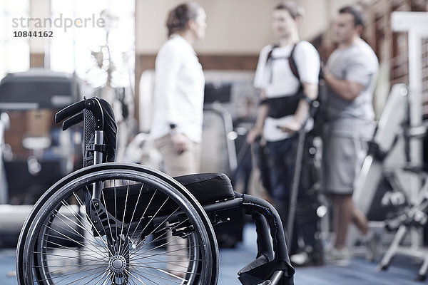 Mann in Physiotherapie mit Rollstuhl im Vordergrund