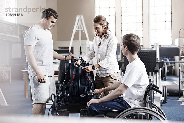 Physiotherapeuten mit Mann im Rollstuhl