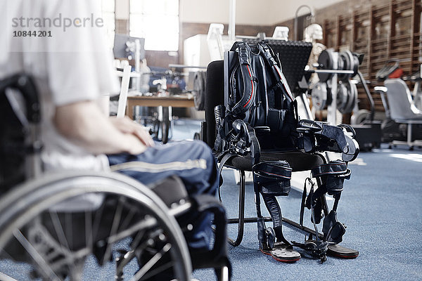 Mann im Rollstuhl in der Nähe von Physiotherapiegeräten