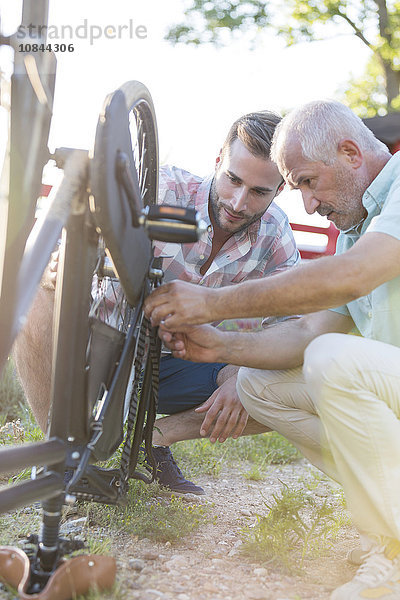 Vater und erwachsener Sohn reparieren Fahrradkette
