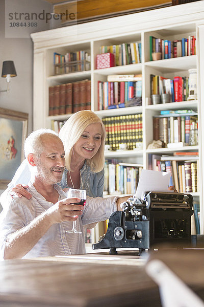 Seniorenpaar trinkt Wein an der Schreibmaschine