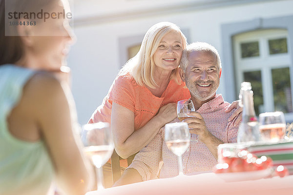 Seniorenpaar lächelt und trinkt Wein auf der Sonnenterrasse