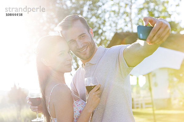 Junges Pärchen mit Wein im sonnigen Hinterhof