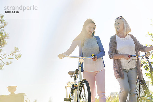 Mutter und erwachsene Tochter gehende Fahrräder