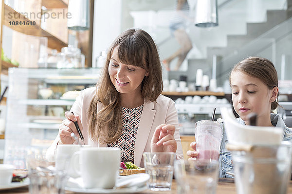 Mutter und Tochter beim Essen und Trinken am Kaffeetisch