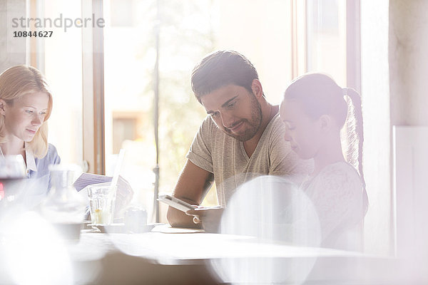 Vater und Tochter mit digitalem Tablett im sonnigen Café