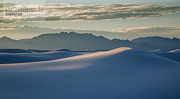Silhouettierte Berge hinter ruhiger weißer Sanddüne  White Sands  New Mexico  USA