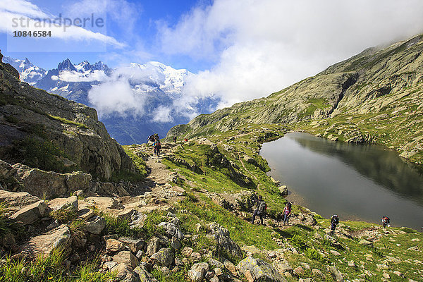 Niedrige Wolken und Nebel um Grandes Jorasses und Mont Blanc  während Wanderer am Lac De Cheserys  Haute Savoie  Französische Alpen  Frankreich  Europa  weitergehen