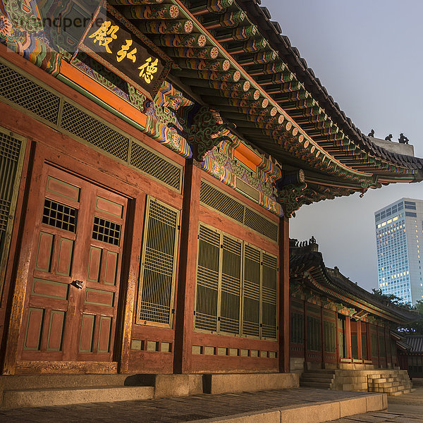 Deoksugung-Palast  traditionelles koreanisches Gebäude  beleuchtet in der Abenddämmerung  mit modernem Gebäude in der Ferne  Seoul  Südkorea  Asien