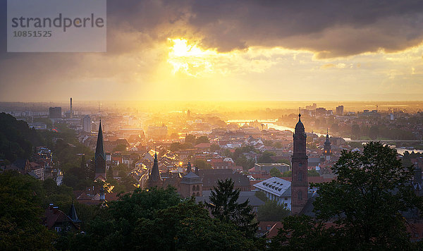 Goldene Nachmittagssonne bricht dramatisch durch Regenwolken über den Türmen der Heidelberger Altstadt  Baden-Württemberg  Deutschland  Europa