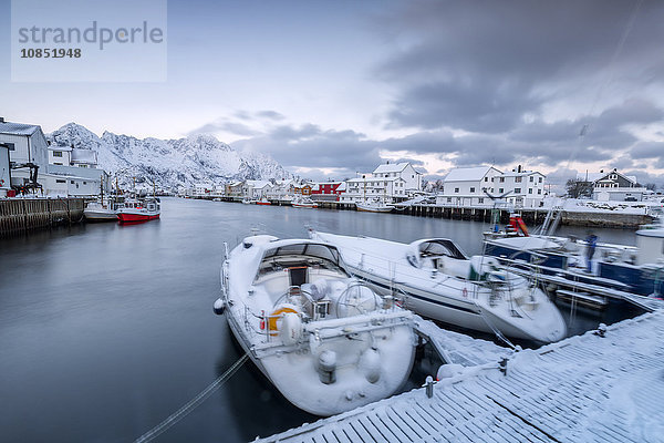 Das typische Fischerdorf Henningsvaer  umgeben von schneebedeckten Bergen und dem kalten Meer  Lofoten Inseln  Arktis  Norwegen  Skandinavien  Europa