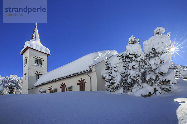 Strahlen der Wintersonne beleuchten die Schneelandschaft und die typische Kirche  Maloja  Engadin  Kanton Graubünden  Schweiz  Europa