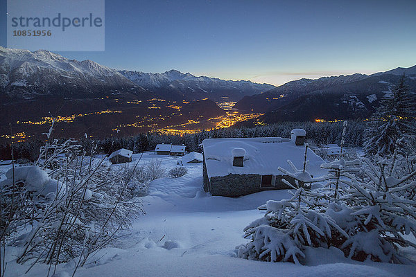 Lichter der Abenddämmerung beleuchten das Tal und die schneebedeckten Hütten  Tagliate Di Sopra  Gerola-Tal  Valtellina  Lombardei  Italien  Europa