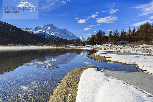 Schneebedeckte Gipfel spiegeln sich im noch teilweise zugefrorenen Silvaplanersee  Maloja  Kanton Graubünden  Engadin  Schweiz  Europa