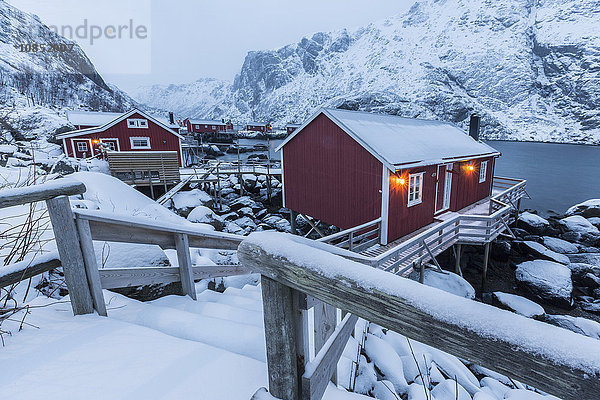 Typische Fischerhäuser  rorbu genannt  in der Schneelandschaft in der Abenddämmerung  Nusfjord  Landkreis Nordland  Lofoten  Norwegen  Skandinavien  Europa