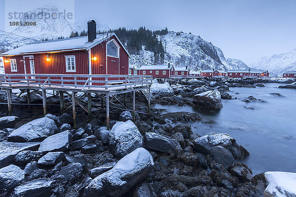 Typische Fischerhäuser  rorbu genannt  in der Schneelandschaft in der Abenddämmerung  Nusfjord  Landkreis Nordland  Lofoten  Norwegen  Skandinavien  Europa