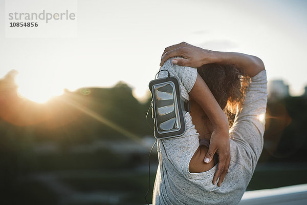 Rear view of woman stretching arm at park