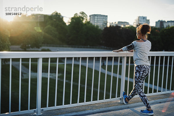 Woman stretching by railing at sidewalk