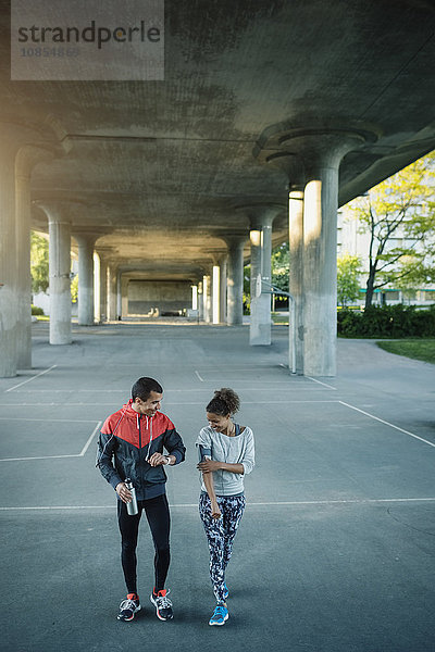 Happy friends walking on street under bridge