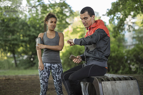 Man looking at wristwatch while woman touching arm band