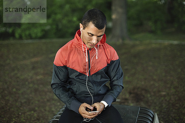 Man sitting on bench listening music at park