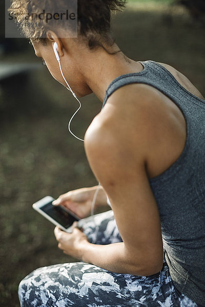 Woman using smart phone while sitting in park