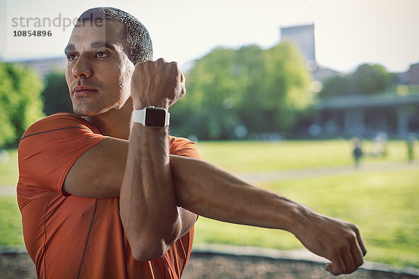 Man wearing wristwatch stretching arm at park