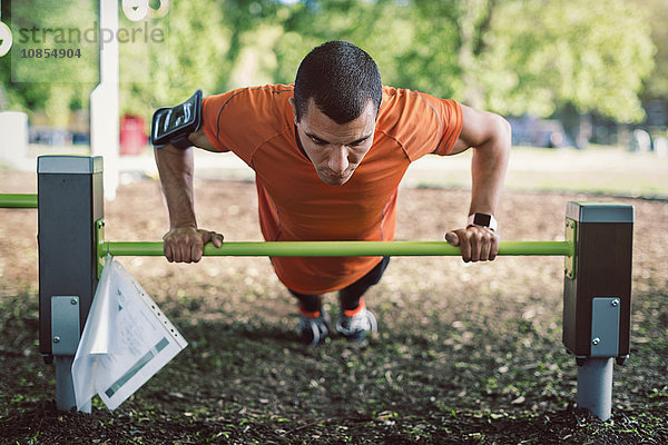 Man doing push-ups on railing at park