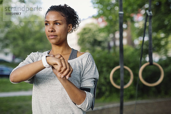 Woman using smart watch while looking away at park