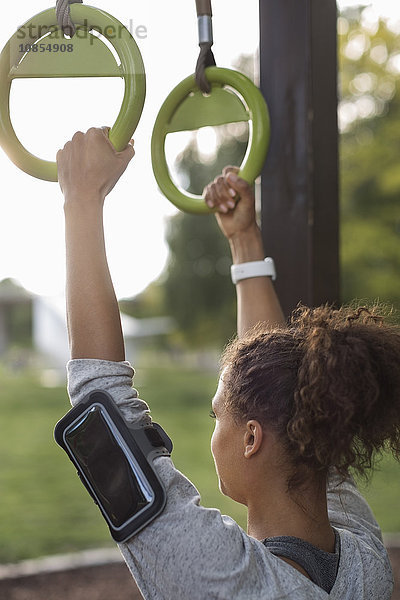 Woman hanging on gymnastic rings at park