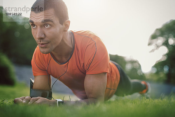 Man in plank position on grassy field at park