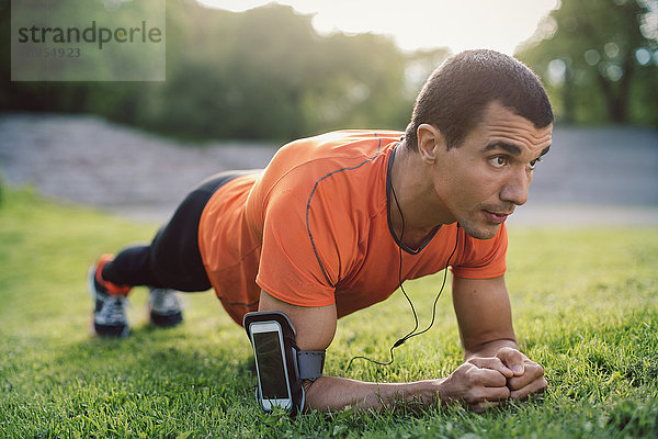 Man doing plank exercise on grassy field at park