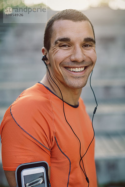 Portrait of smiling man wearing headphones at park