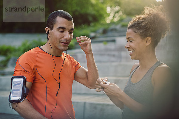 Man hearing music with headphones while woman smiling at steps