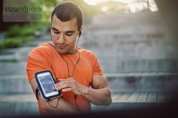 Man using smart phone armband while standing at steps