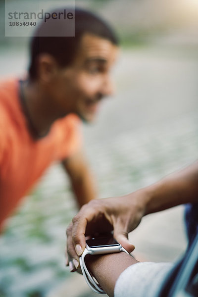 Woman using smart watch while man doing push-ups