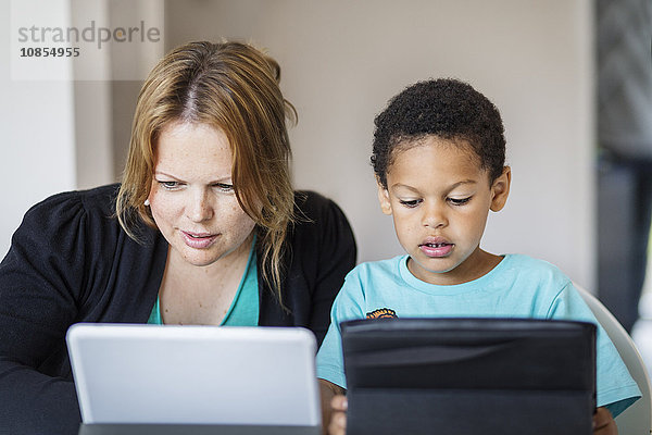 Mother and son using digital tablets at home