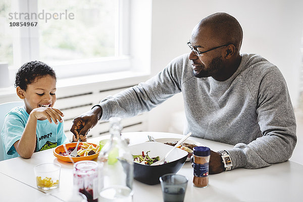 Father having food with son at dining table in house