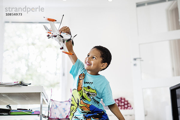 Happy boy playing with model airplane at home