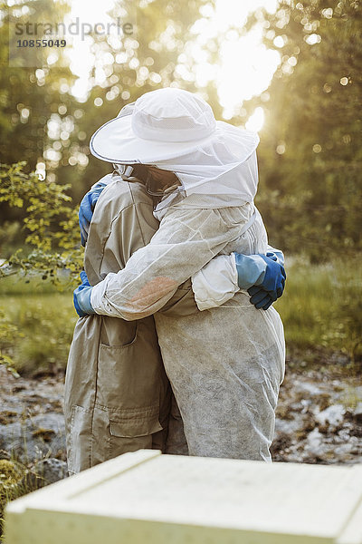 Side view of beekeepers embracing on field