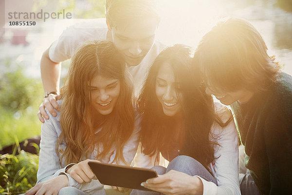 Happy Teenagers using digital tablet together on sunny day