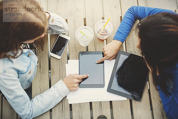 Directly above shot of female teenagers touching digital tablet at table