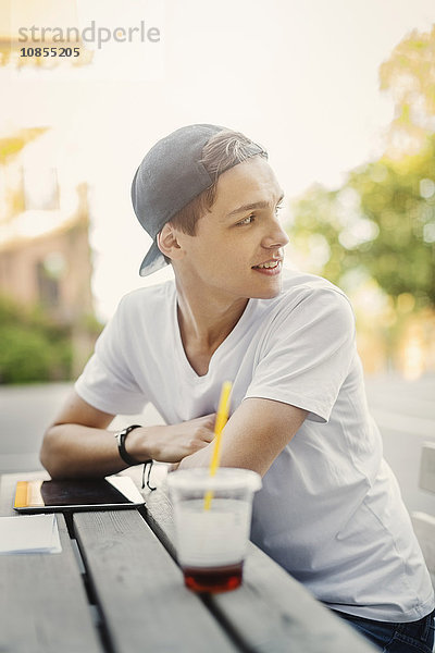 Male teenager looking away while sitting at table outdoors