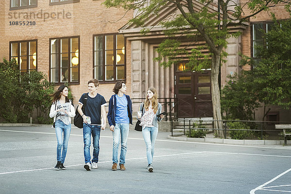 Friends talking while walking on street outside building