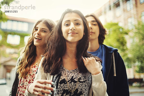 Portrait of confident teenager standing with friends outdoors
