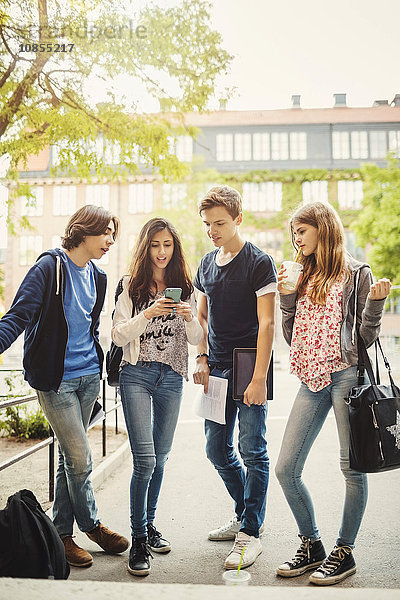 Full length of teenagers using smart phone on street