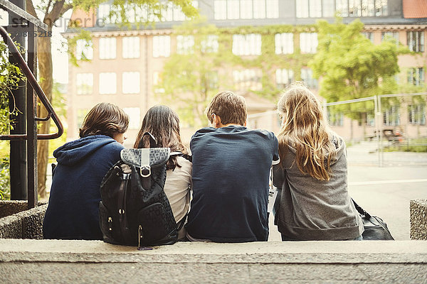 Rear view of teenagers sitting on steps outdoors