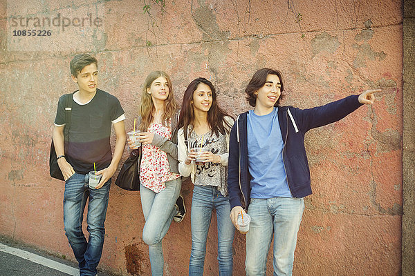 Happy teenager showing something to friends against wall