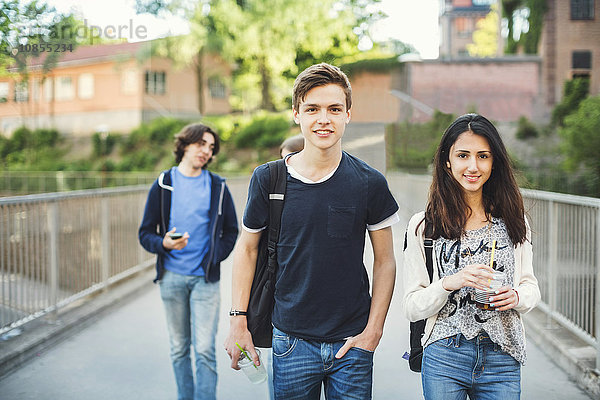 Portrait of smiling teenagers walking on bridge