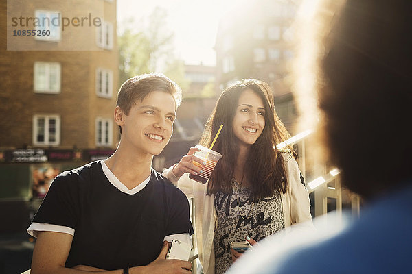 Happy teenagers looking away while standing outdoors